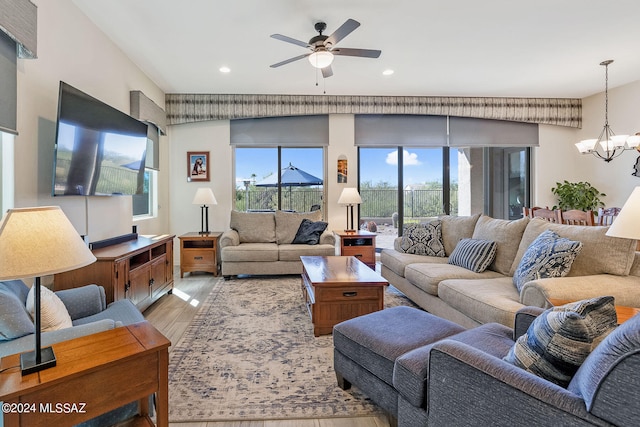 living room featuring ceiling fan with notable chandelier and light hardwood / wood-style floors