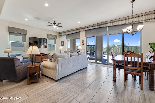 living room with ceiling fan with notable chandelier and light hardwood / wood-style flooring