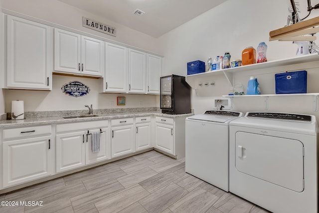 laundry room featuring cabinets, sink, and washer and dryer