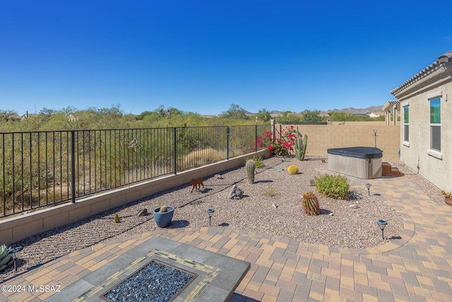 view of patio / terrace featuring a hot tub and an outdoor fire pit