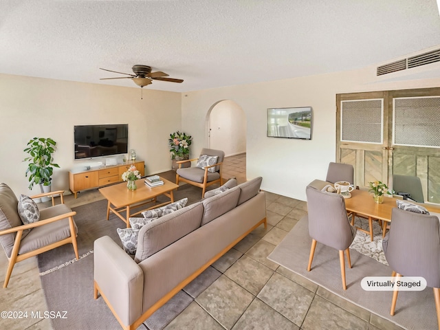 tiled living room with ceiling fan and a textured ceiling