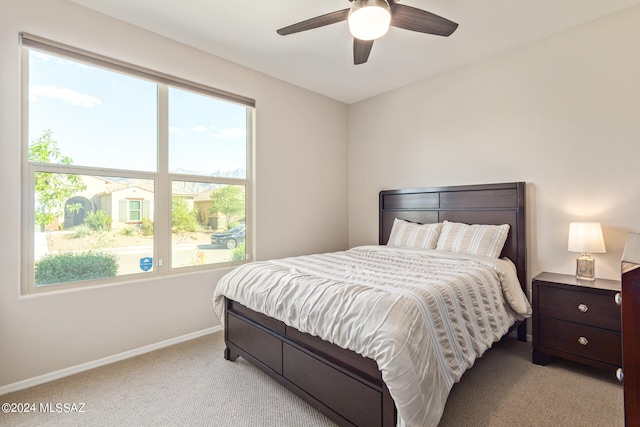 bedroom with ceiling fan, multiple windows, and light colored carpet