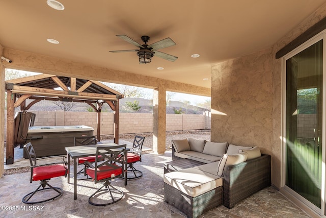 view of patio / terrace featuring a hot tub, a gazebo, an outdoor living space, and ceiling fan