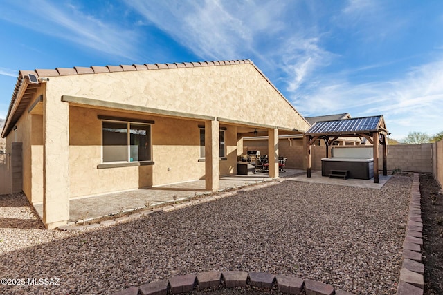 rear view of house featuring a patio area and a hot tub