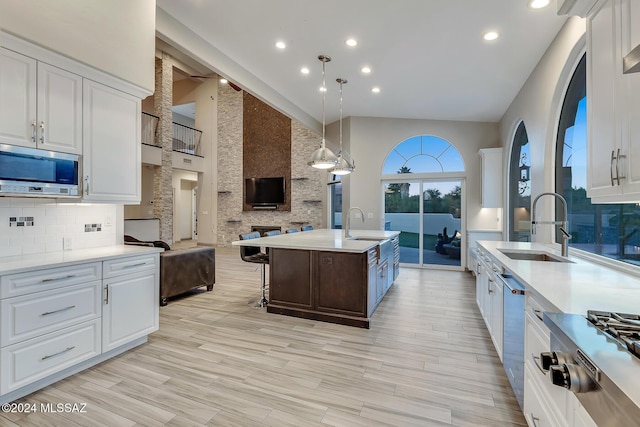 kitchen featuring a kitchen island with sink, high vaulted ceiling, white cabinets, light hardwood / wood-style floors, and stainless steel appliances