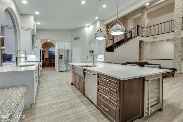 kitchen featuring appliances with stainless steel finishes, dark brown cabinets, light hardwood / wood-style flooring, high vaulted ceiling, and hanging light fixtures