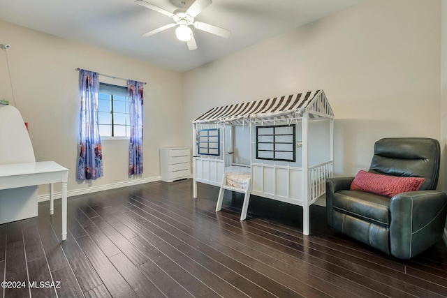 sitting room with ceiling fan and dark wood-type flooring