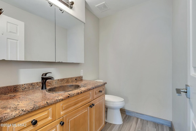 bathroom featuring vanity, hardwood / wood-style flooring, and toilet