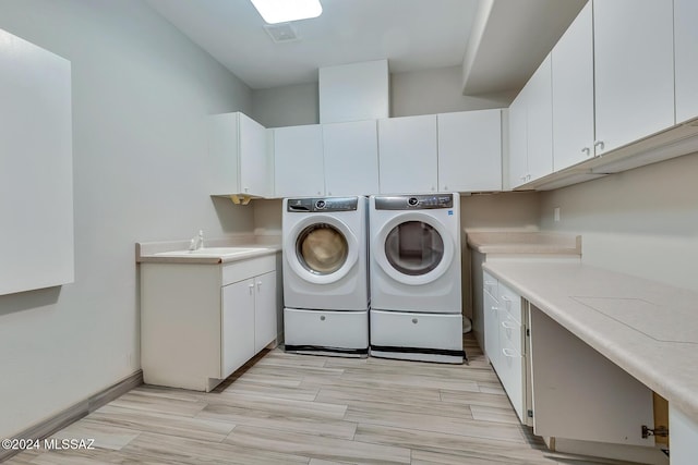 clothes washing area with separate washer and dryer, cabinets, sink, and light hardwood / wood-style floors