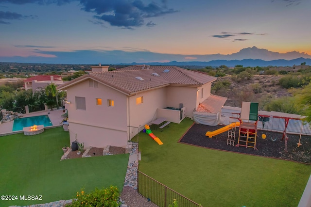 exterior space with a lawn, a mountain view, a fenced in pool, and a playground