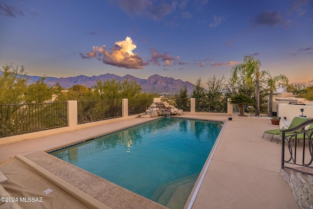 pool at dusk featuring a mountain view and a patio