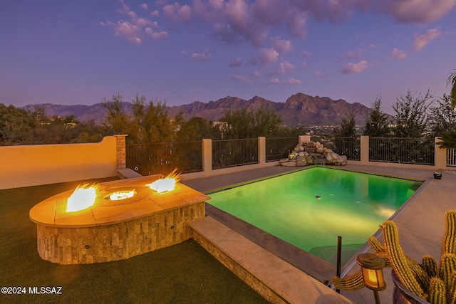 pool at dusk with a mountain view and an outdoor fire pit