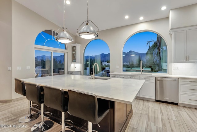 kitchen featuring sink, light stone counters, a mountain view, an island with sink, and white cabinets