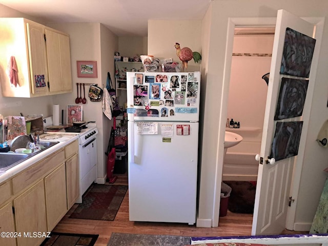 kitchen featuring light brown cabinets, white appliances, a sink, light countertops, and light wood-type flooring