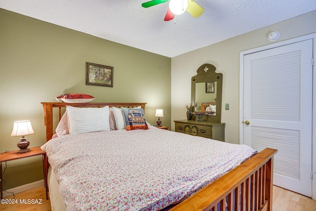 bedroom with light wood-style flooring, ceiling fan, and a textured ceiling