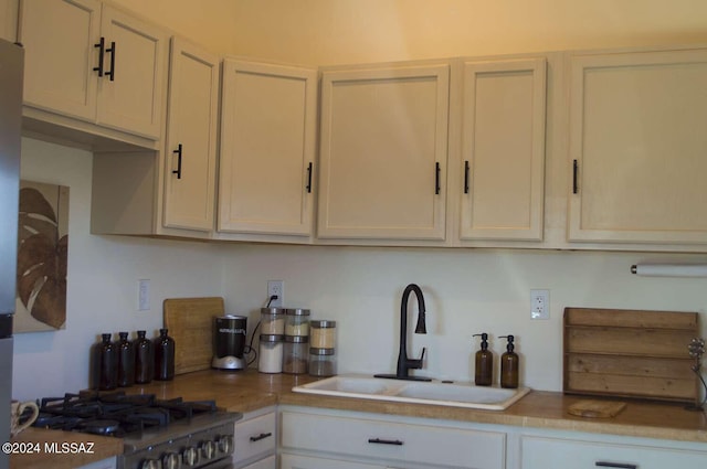 kitchen with stainless steel range, white cabinets, and sink