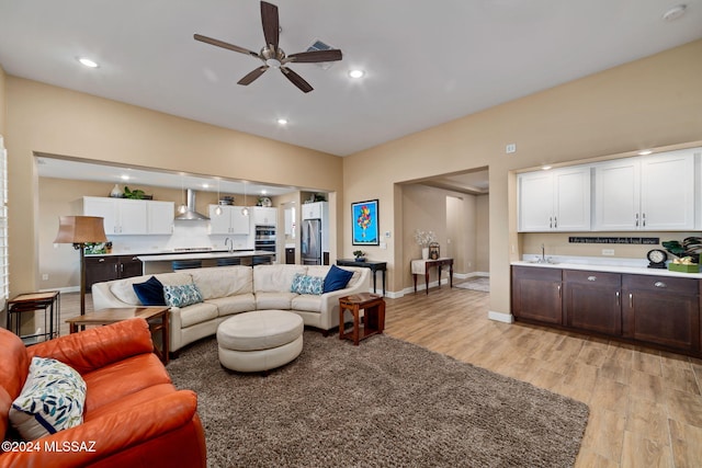 living room with sink, ceiling fan, and light wood-type flooring