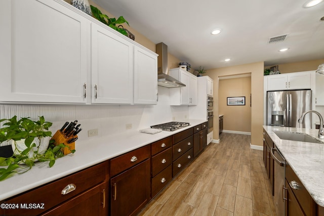 kitchen featuring stainless steel appliances, white cabinetry, sink, and wall chimney exhaust hood