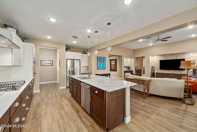 kitchen with sink, hanging light fixtures, stainless steel appliances, a kitchen island with sink, and white cabinets