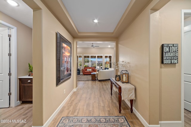 corridor featuring light hardwood / wood-style flooring and a raised ceiling