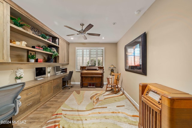 office area with built in desk, ceiling fan, and light wood-type flooring