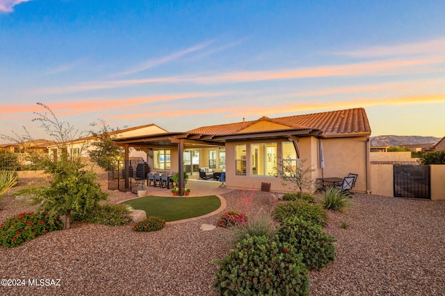 back house at dusk featuring a mountain view and a patio