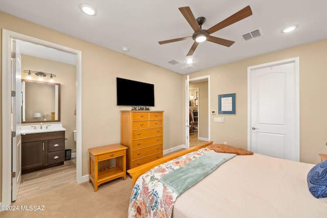 bedroom featuring connected bathroom, light colored carpet, and ceiling fan