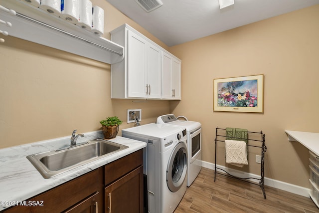 laundry room with light hardwood / wood-style floors, cabinets, washer and clothes dryer, and sink