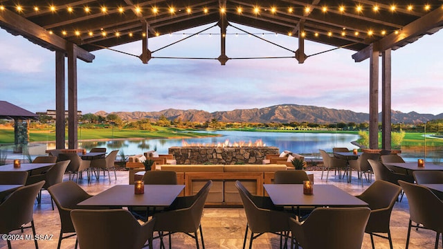 patio terrace at dusk with exterior bar and a water and mountain view