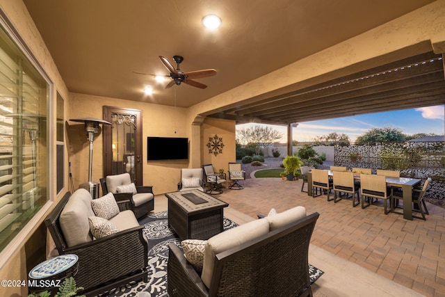 view of patio / terrace with ceiling fan and an outdoor living space with a fire pit