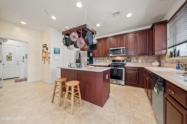 kitchen featuring a kitchen island, visible vents, light countertops, appliances with stainless steel finishes, and decorative backsplash