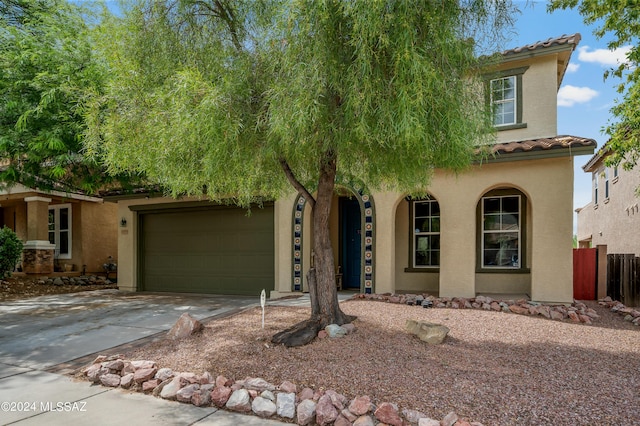 view of front of house with concrete driveway, fence, a tiled roof, and stucco siding