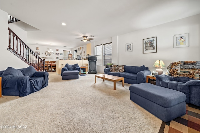 carpeted living room with ceiling fan with notable chandelier