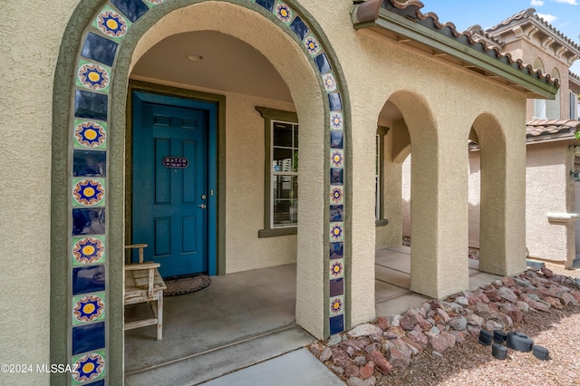 property entrance with a tile roof and stucco siding