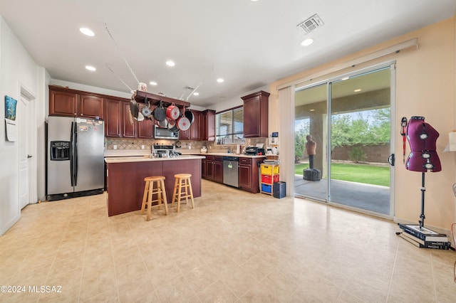 kitchen with appliances with stainless steel finishes, a center island, a breakfast bar area, and backsplash