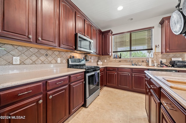 kitchen featuring tasteful backsplash, stainless steel appliances, light stone countertops, and sink