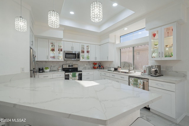 kitchen with appliances with stainless steel finishes, sink, kitchen peninsula, decorative light fixtures, and white cabinets