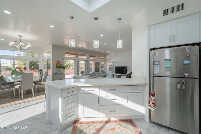 kitchen with stainless steel refrigerator, kitchen peninsula, and white cabinets