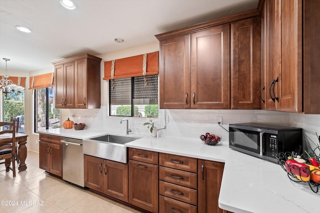 kitchen featuring sink, hanging light fixtures, stainless steel dishwasher, light tile patterned flooring, and a chandelier