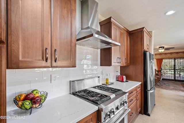 kitchen featuring wall chimney exhaust hood, ceiling fan, decorative backsplash, and appliances with stainless steel finishes