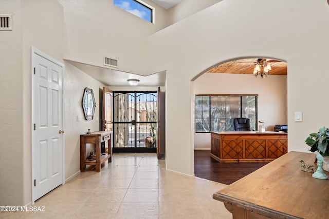 foyer with light tile patterned floors, a high ceiling, and an inviting chandelier