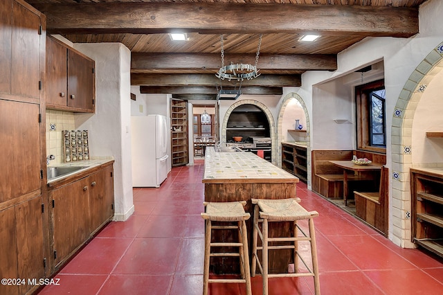 kitchen with tasteful backsplash, dark tile patterned flooring, decorative light fixtures, wooden ceiling, and white fridge