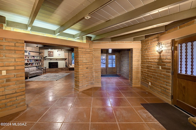 interior space with beamed ceiling, brick wall, dark tile patterned floors, and french doors