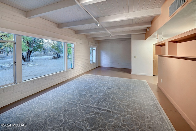 empty room with brick wall, beam ceiling, and wooden ceiling