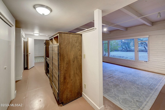 hallway with light tile patterned floors and beam ceiling