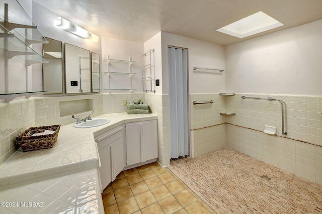 bathroom featuring tile patterned floors, a skylight, tile walls, and vanity