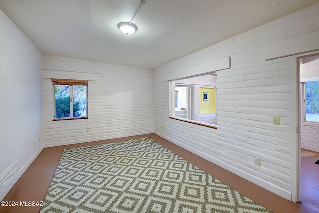 empty room with a healthy amount of sunlight and brick wall