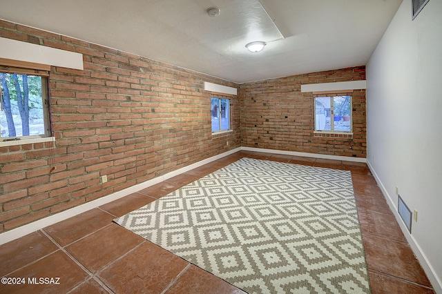 spare room with tile patterned flooring and brick wall