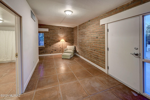 interior space featuring tile patterned flooring and brick wall