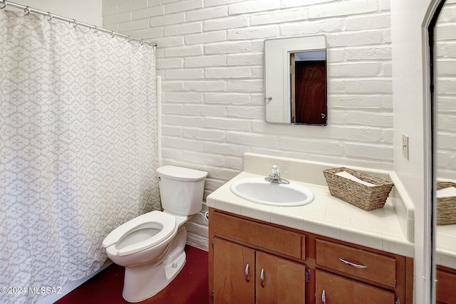 bathroom featuring brick wall, toilet, and vanity